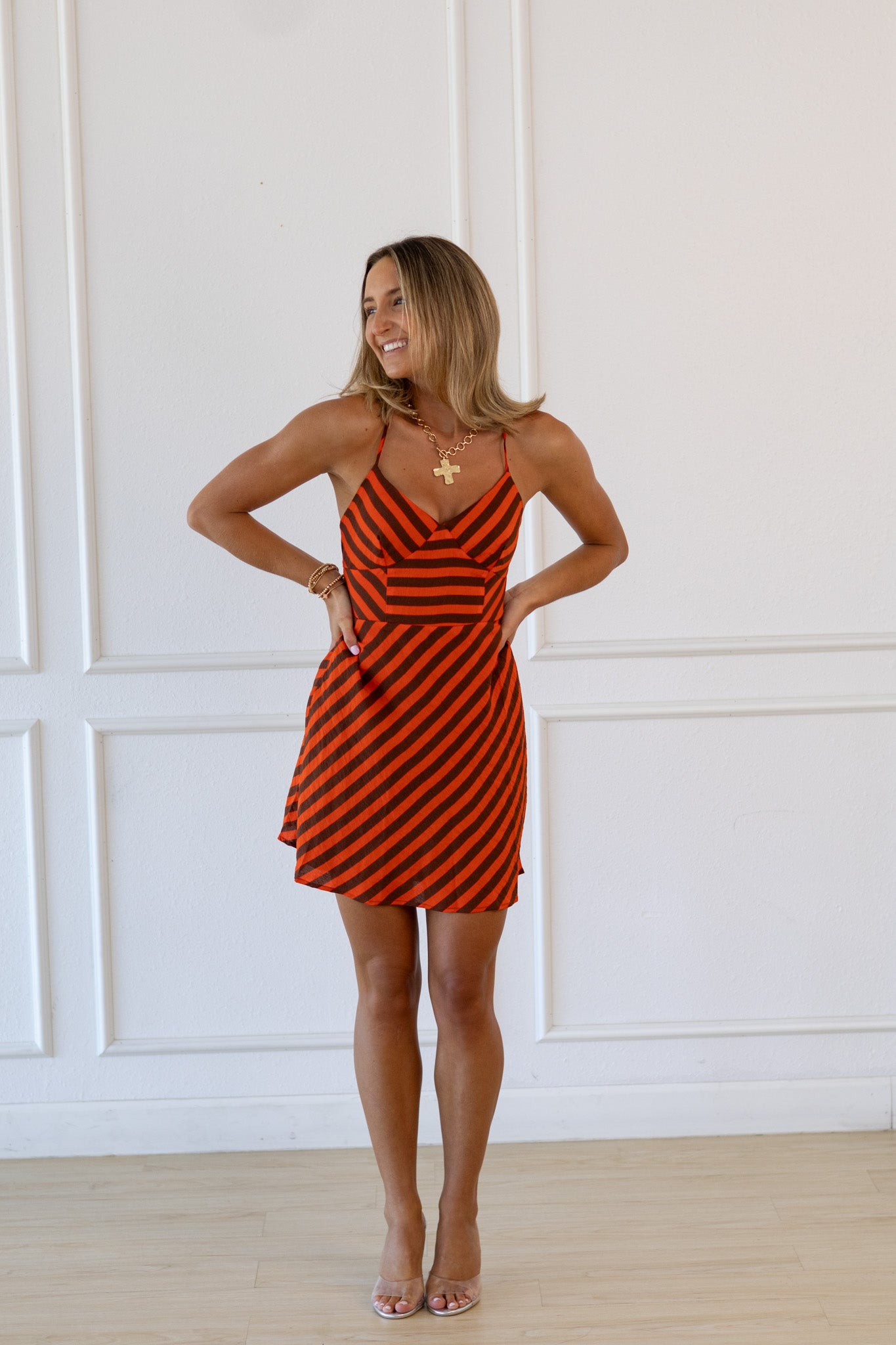 Woman wearing a red and black striped dress against a white paneled wall.