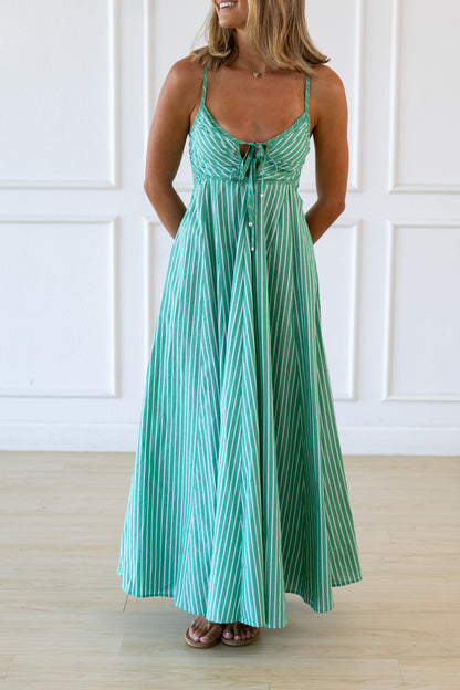 Woman wearing a green and white striped dress against a white paneled wall.