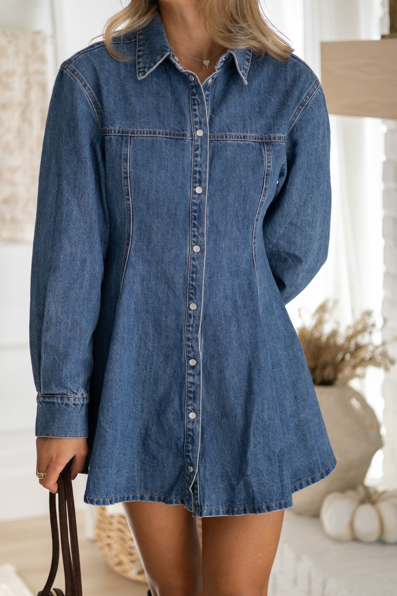 Person wearing a denim shirt dress in a home setting
