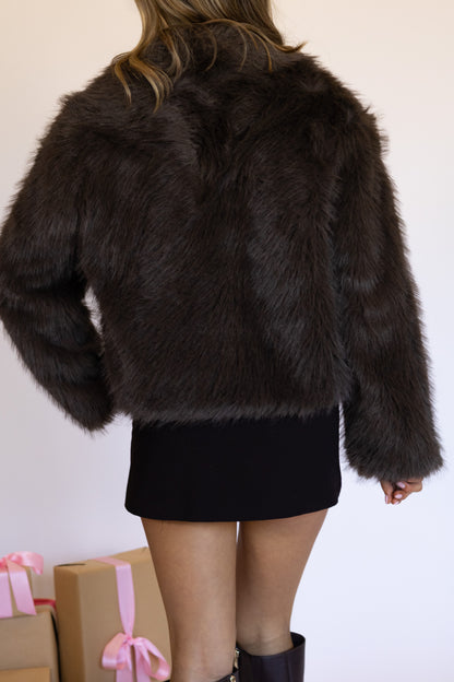 Person wearing a black fur coat with a plain background