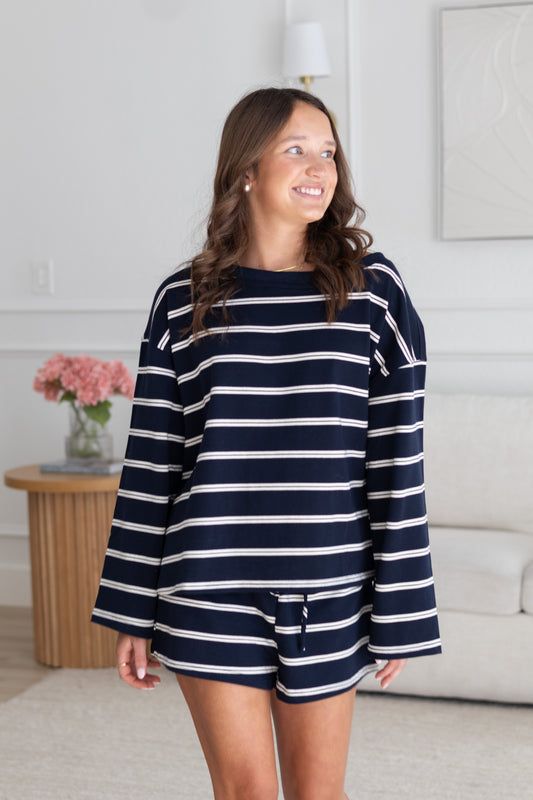Woman wearing a navy and white striped outfit in a living room setting.