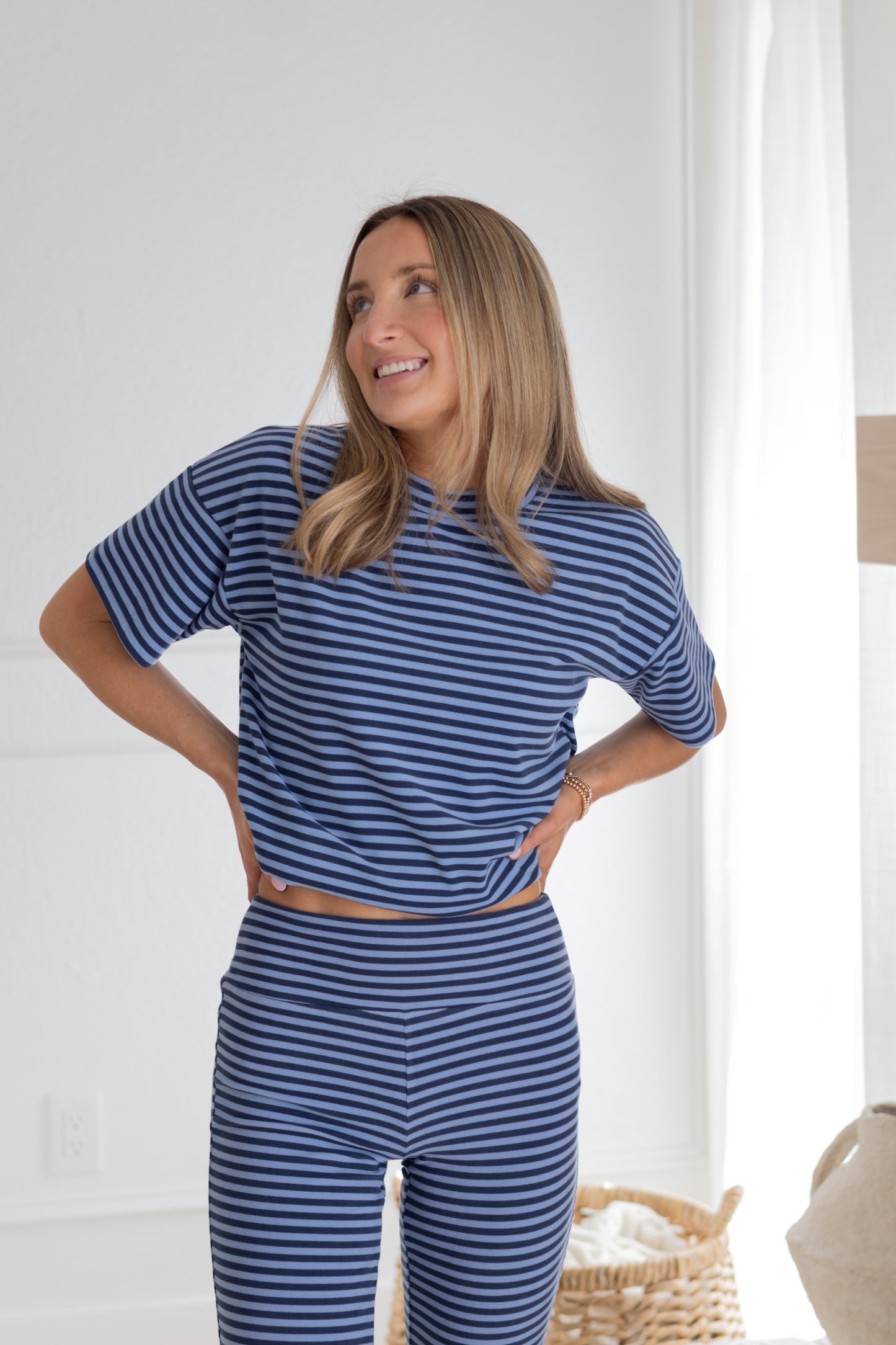 Woman wearing a blue striped outfit standing in a bright room.