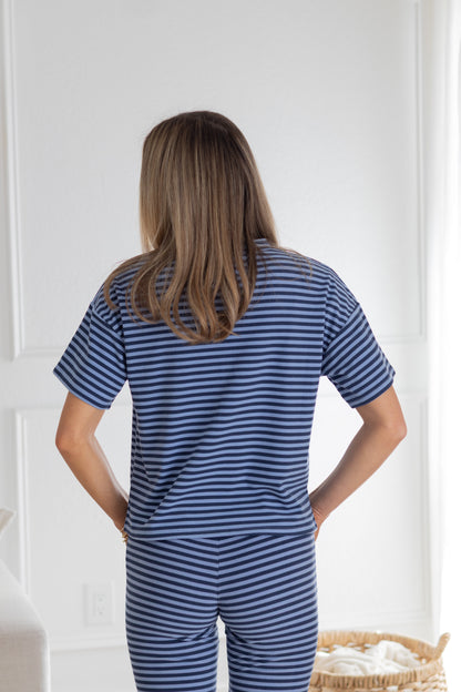 Person wearing a blue and white striped pajama set in a room with a white door and light-colored floor.