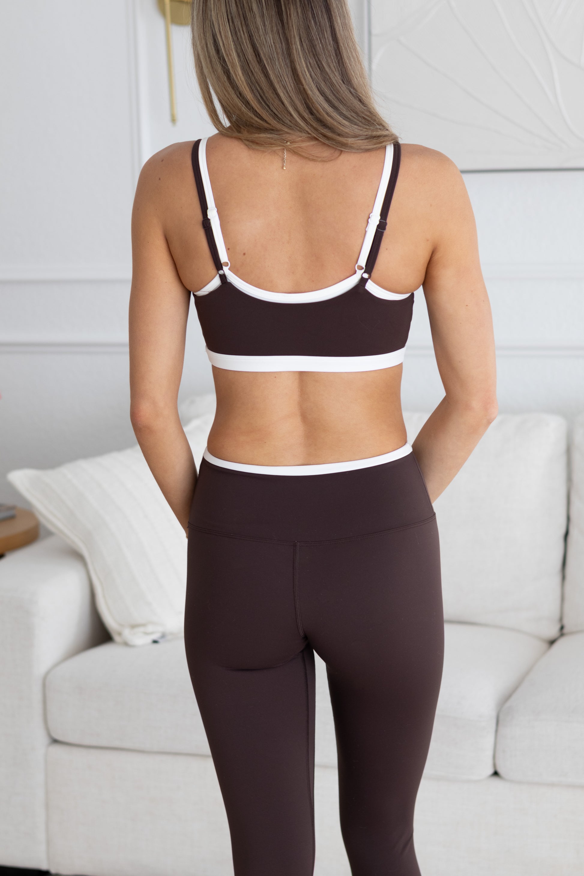 Person wearing a brown sports bra and leggings set in a living room setting.