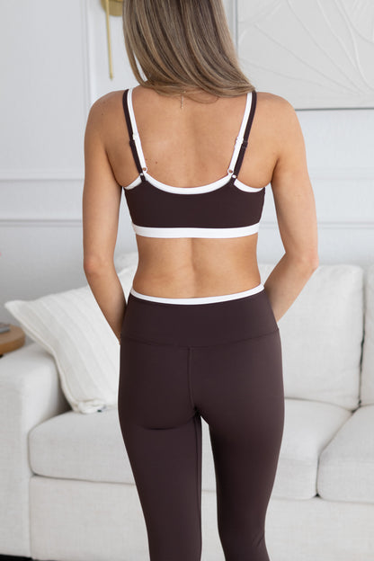 Person wearing a brown sports bra and leggings set in a living room setting.