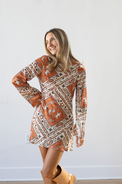 Woman wearing a patterned dress with long sleeves against a white background