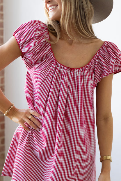 Woman wearing a red and white checkered dress with a plain background