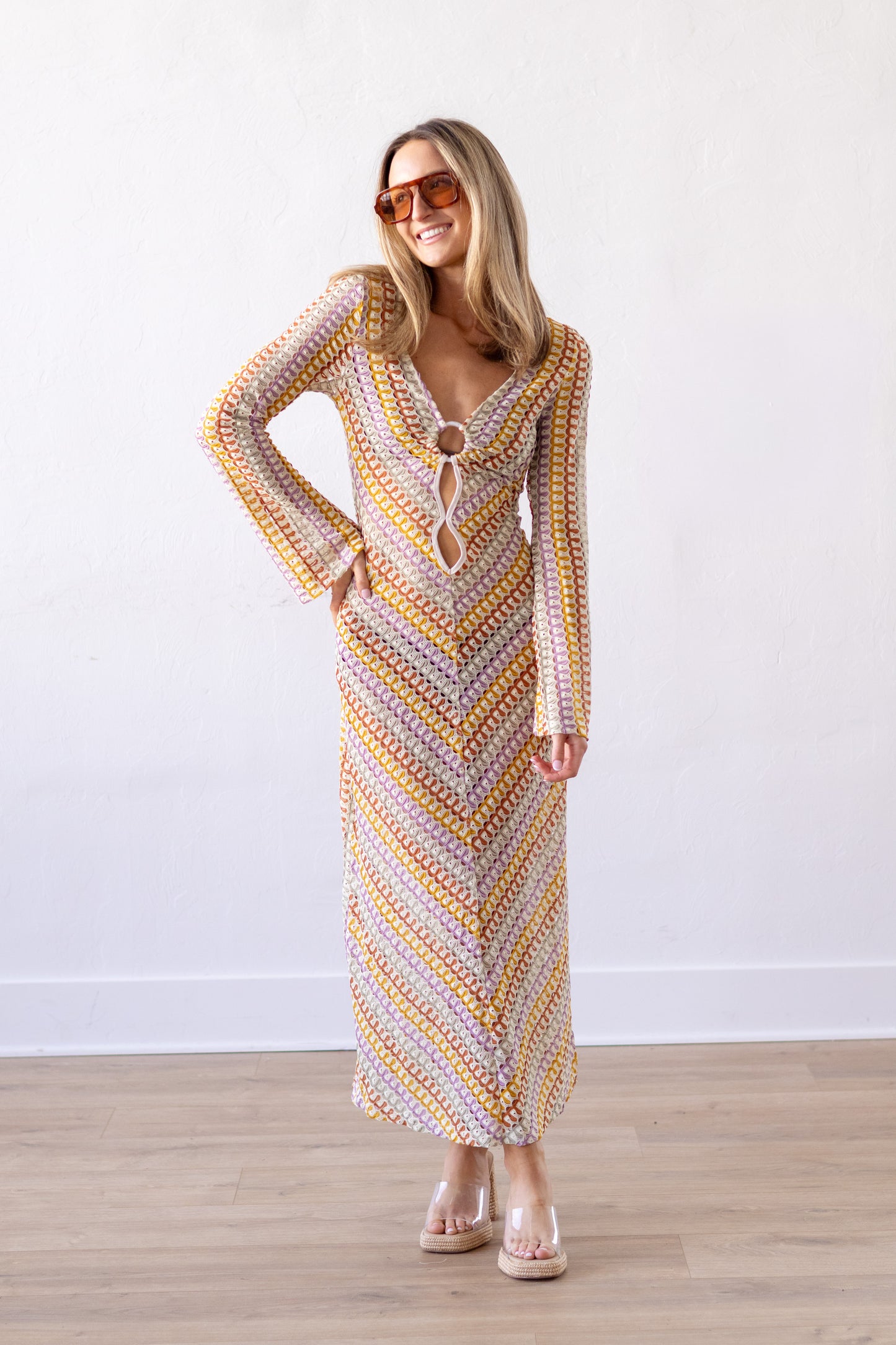 Woman wearing a patterned dress standing against a white wall.