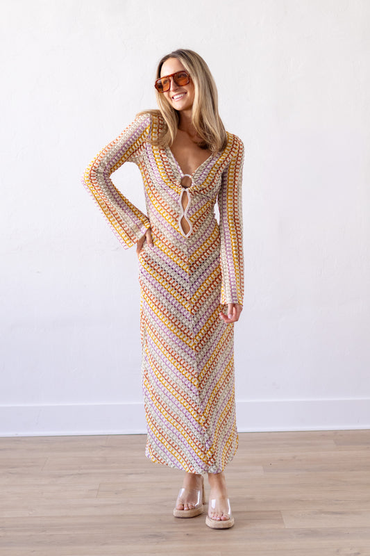 Woman wearing a patterned dress standing against a white wall.
