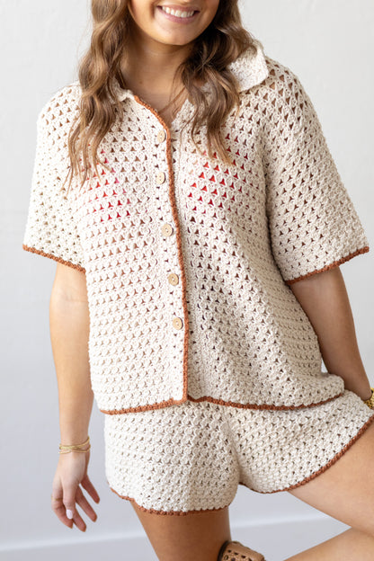 Person wearing a crochet outfit with a matching jacket and shorts on a plain background