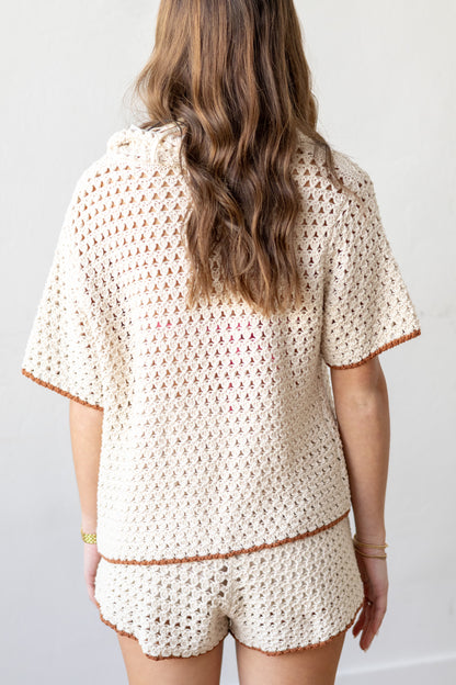 Person wearing a beige crochet top and shorts set against a white background