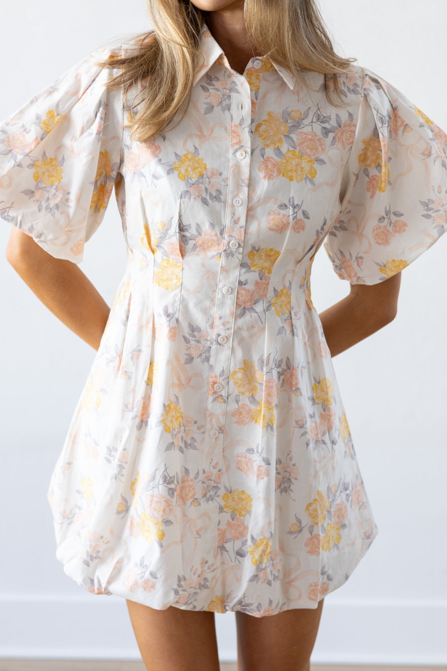 Woman wearing a floral dress with puff sleeves against a white background