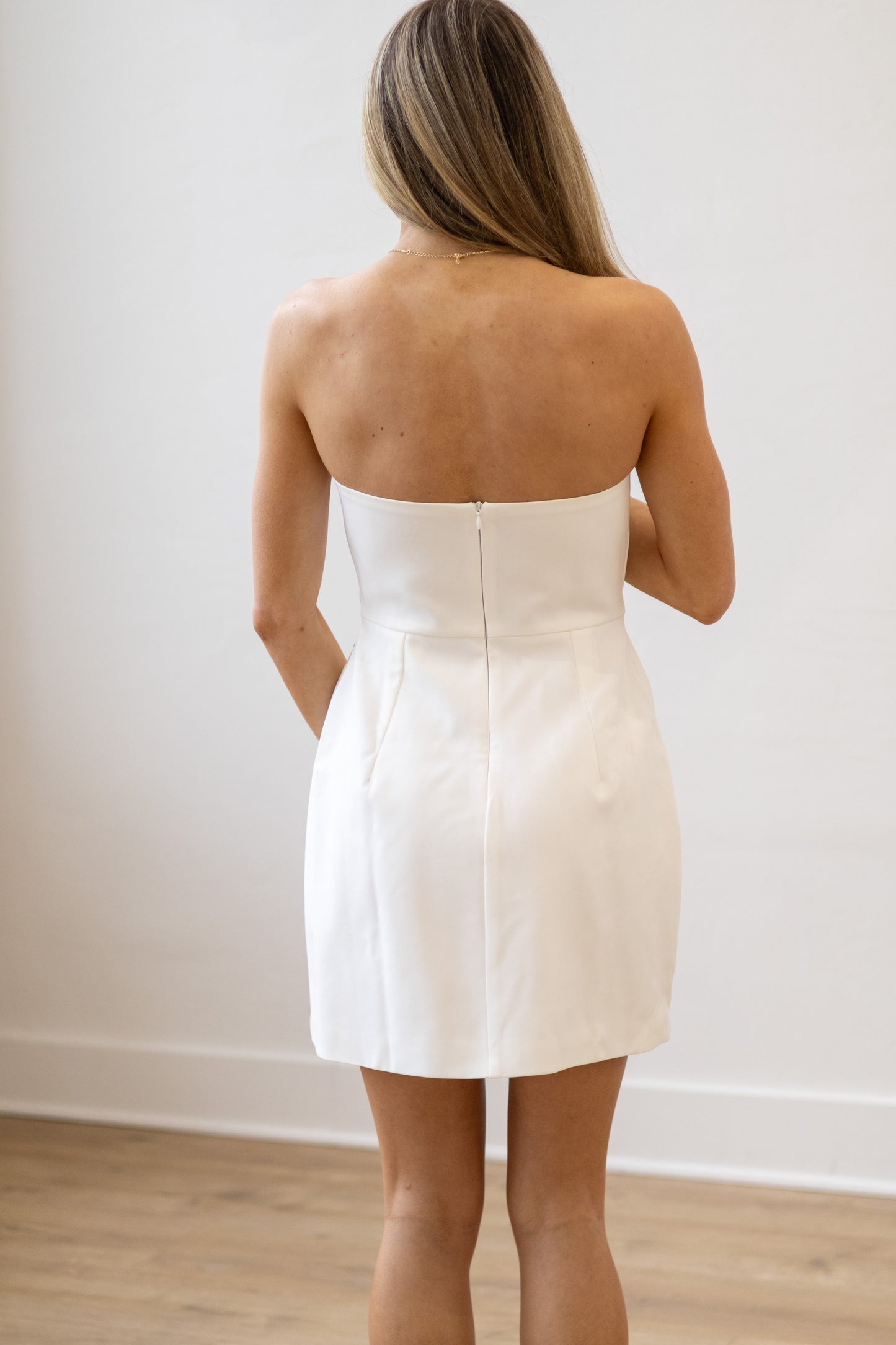 Woman wearing a strapless white dress against a plain background