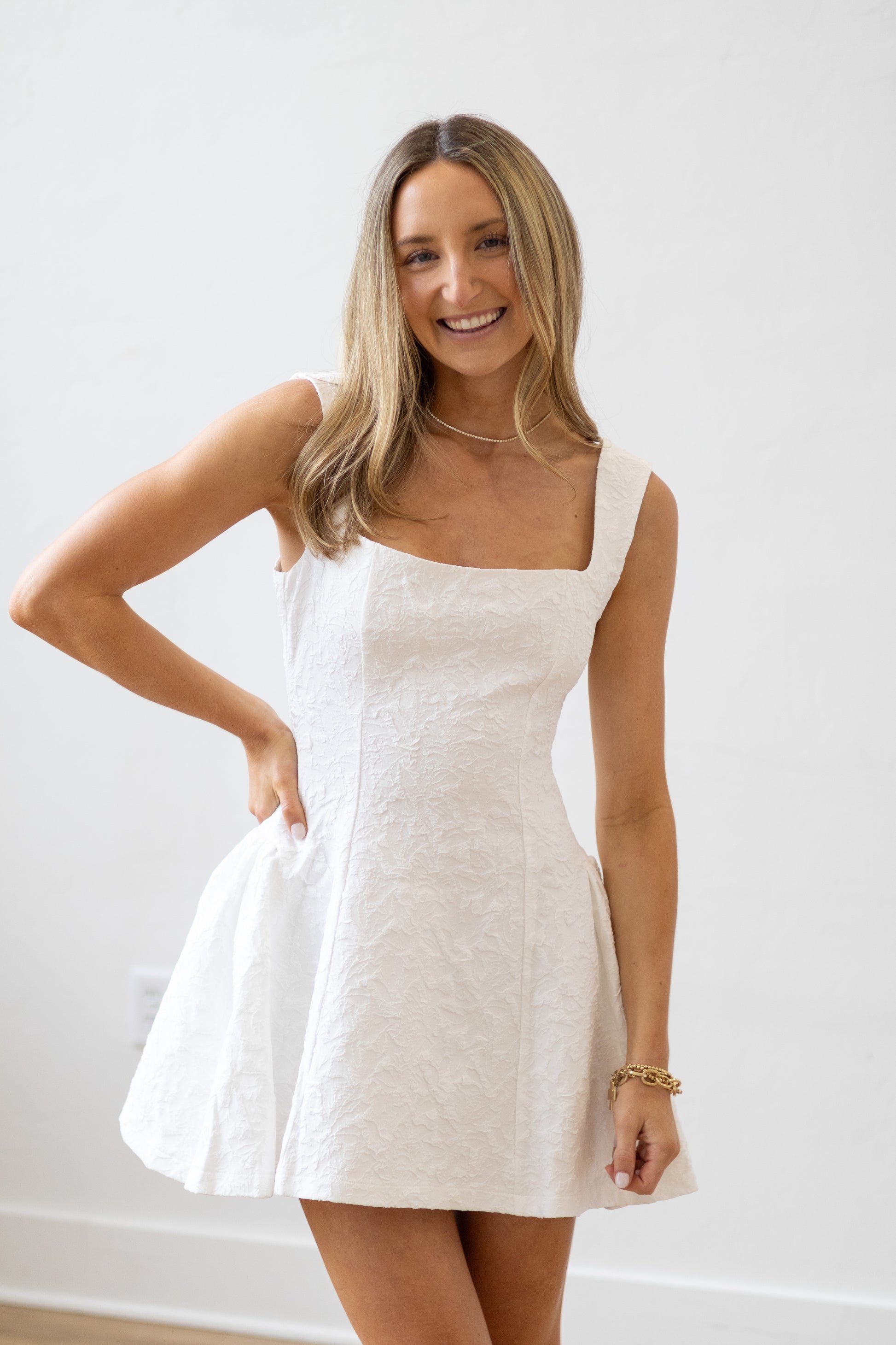 Woman wearing a white dress against a plain background
