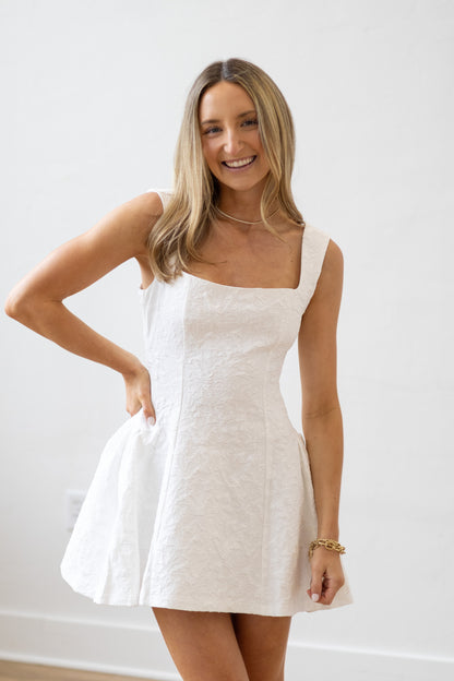 Woman wearing a white dress against a plain background