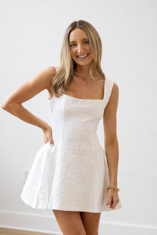 Woman wearing a white dress against a plain background
