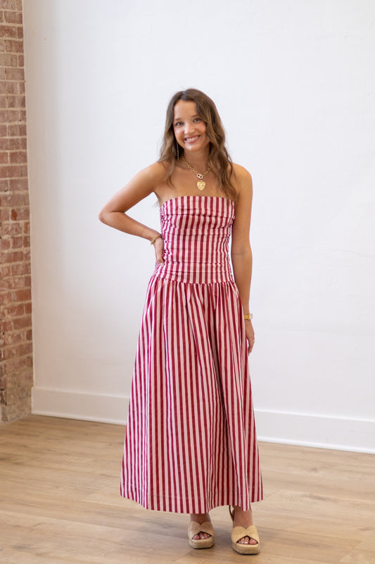 Woman wearing a red and white striped dress standing against a white wall.