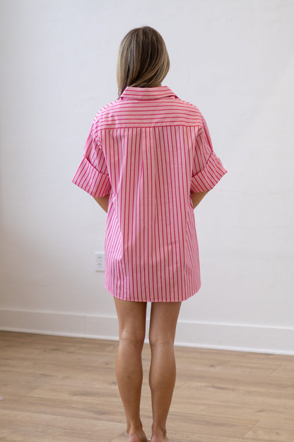 Person wearing a pink and white striped shirt in a minimal indoor setting