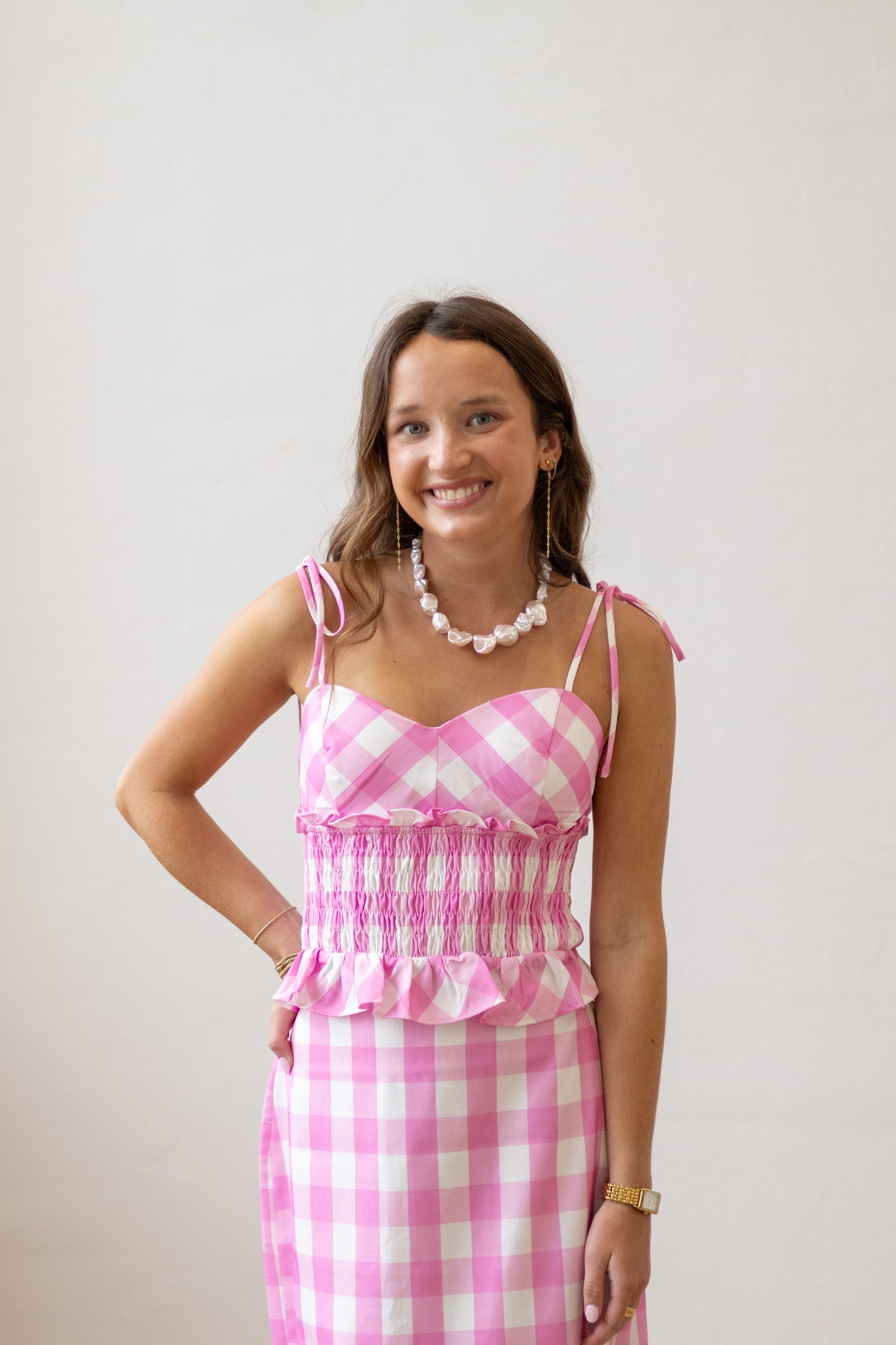 Woman wearing a pink and white checkered dress with a plain background