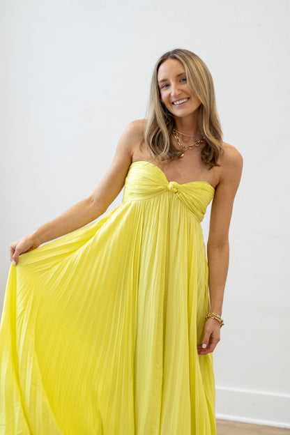 Woman wearing a yellow strapless dress against a white background