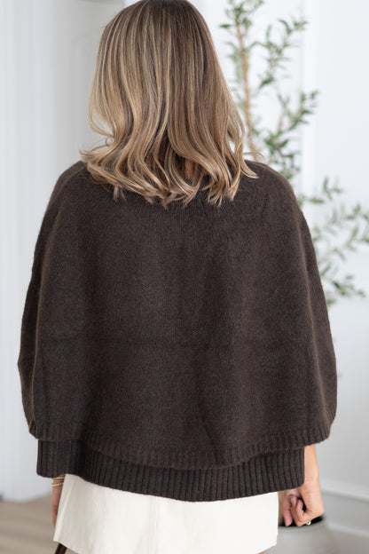 Person wearing a brown knitted sweater with a neutral background