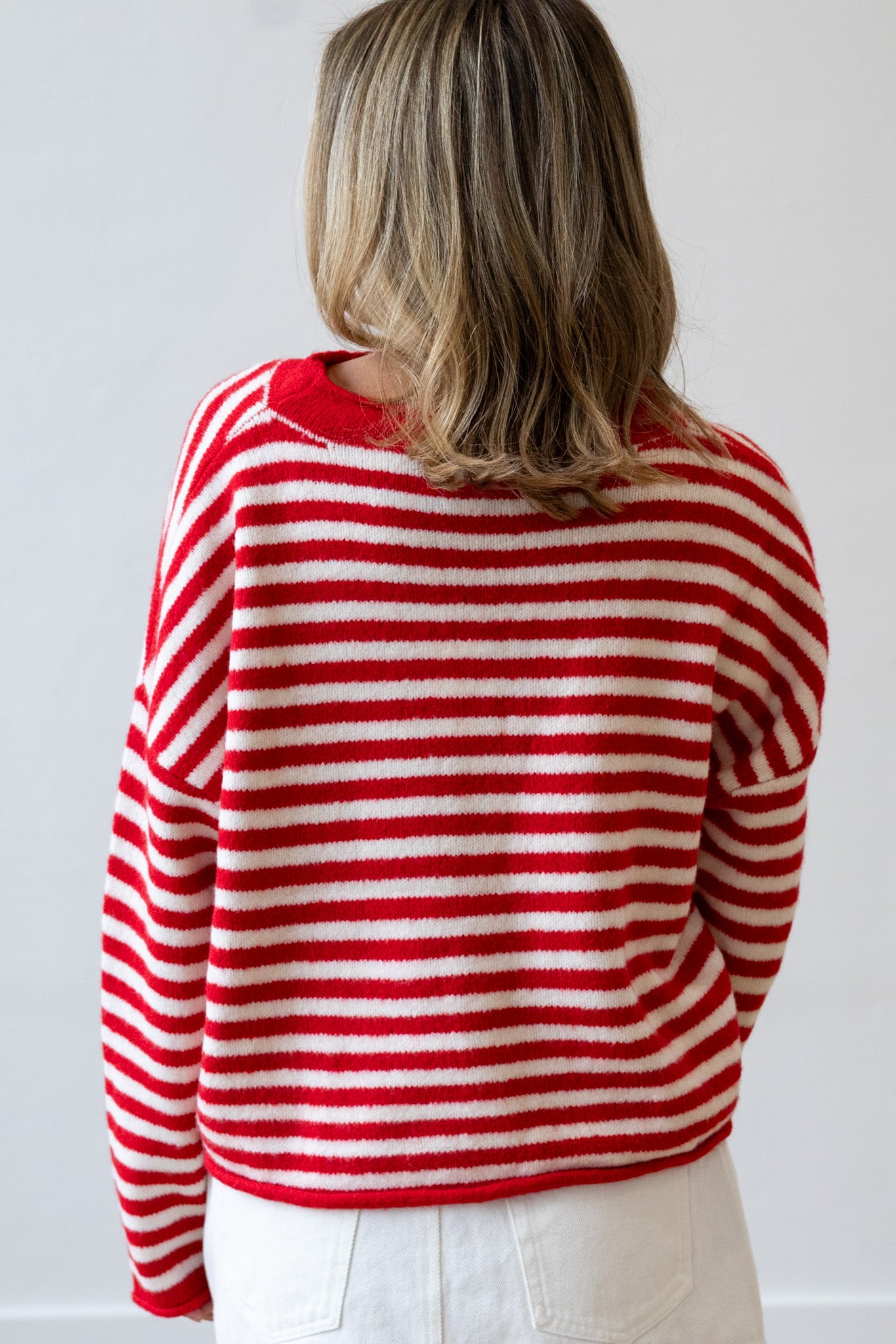 Person wearing a red and white striped sweater against a plain background
