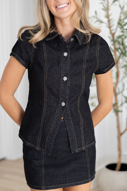 Woman wearing a black denim dress with a white background