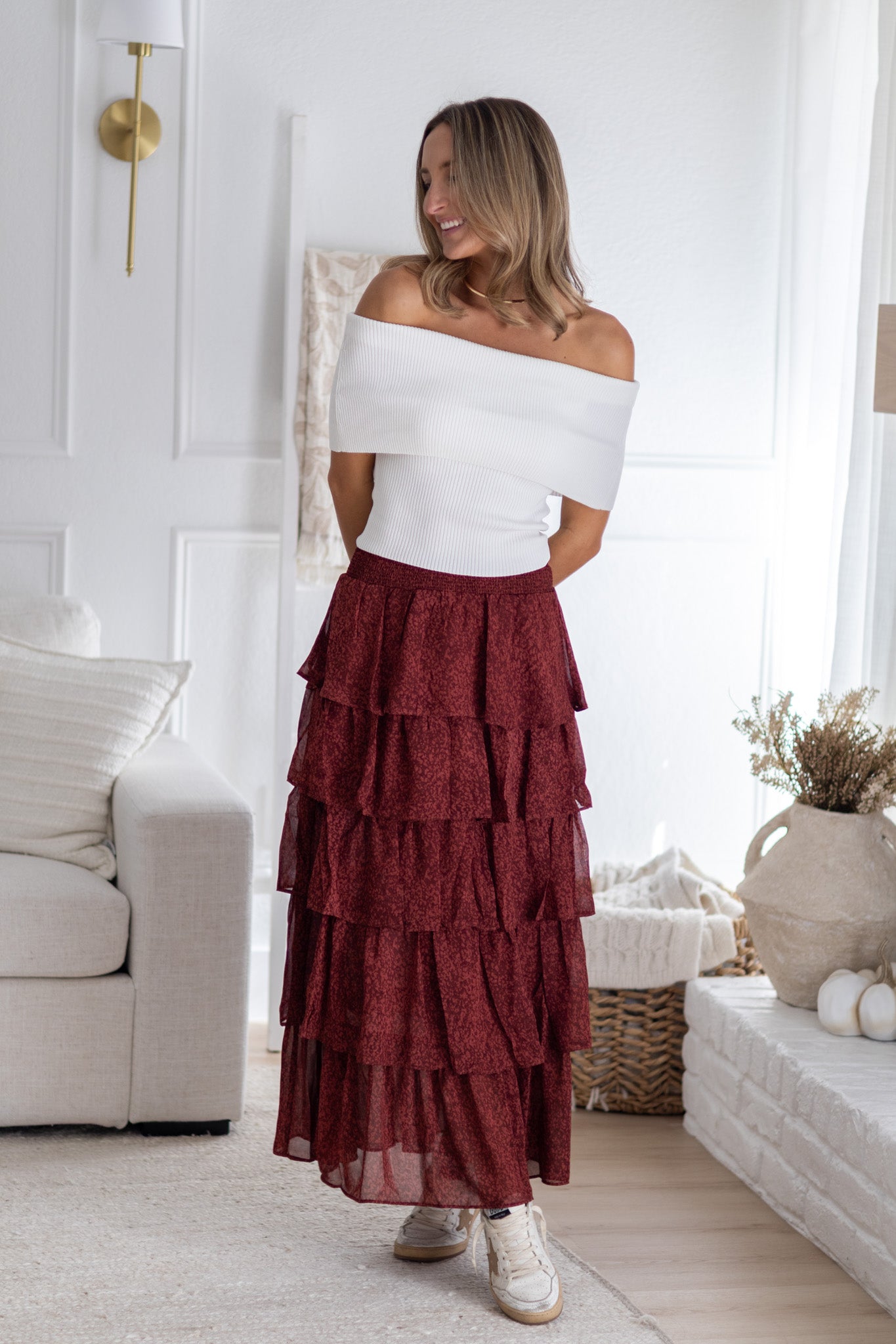 Woman wearing a white top and red tiered skirt in a living room.