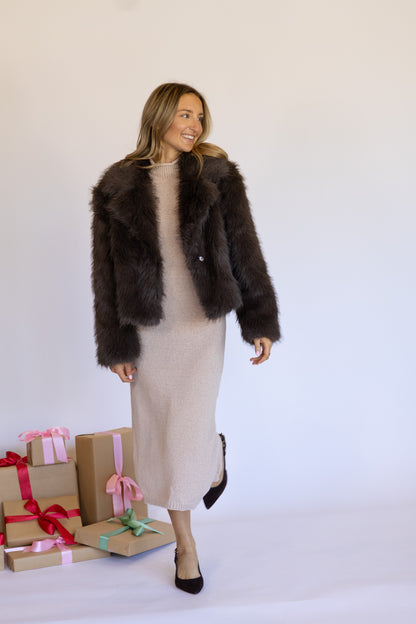 Woman wearing a brown fur coat with gift boxes on a white background