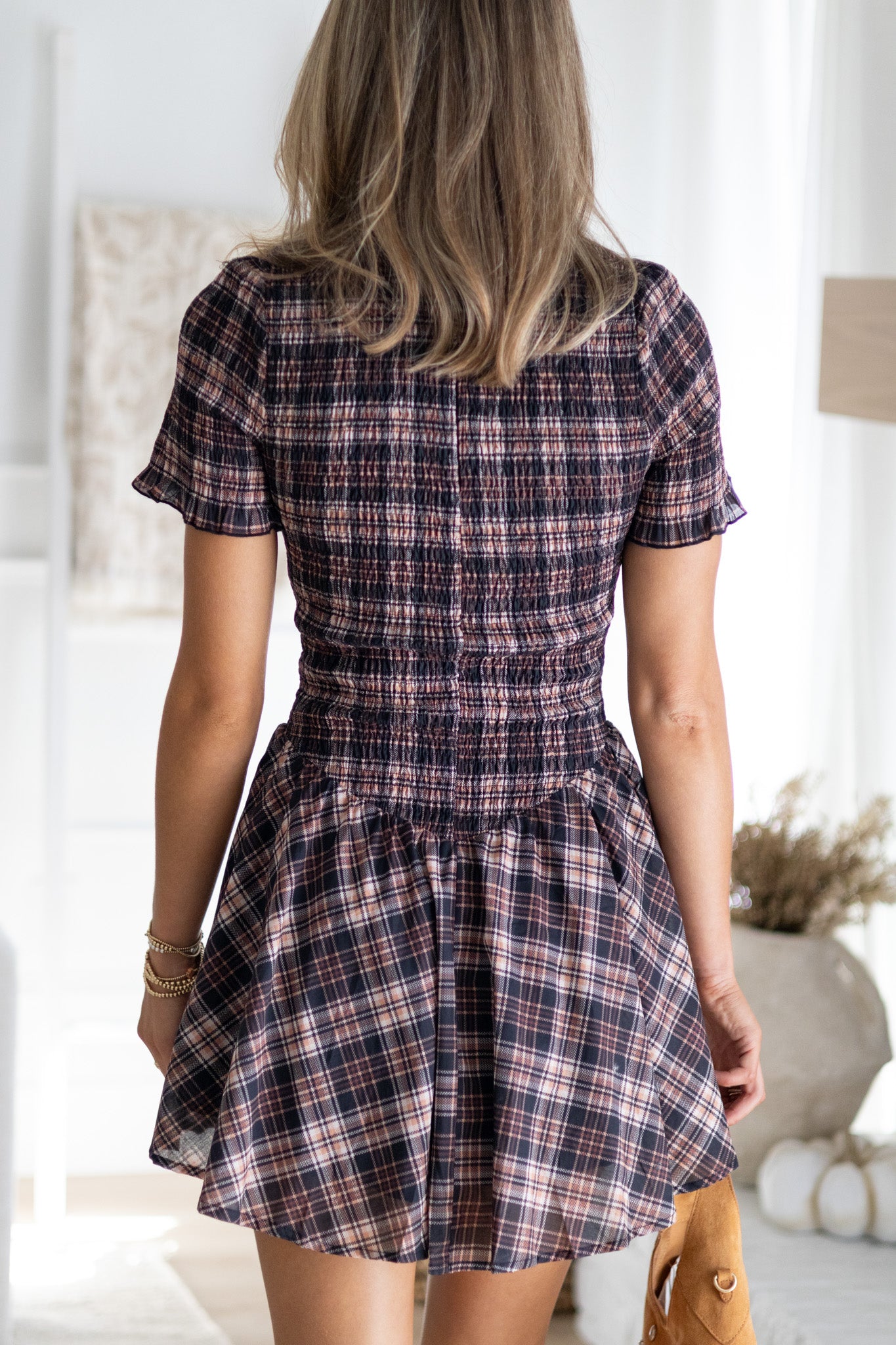 Person wearing a plaid dress in a bright room