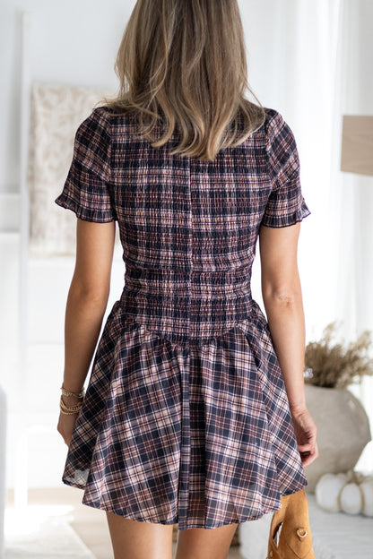 Person wearing a plaid dress in a bright room